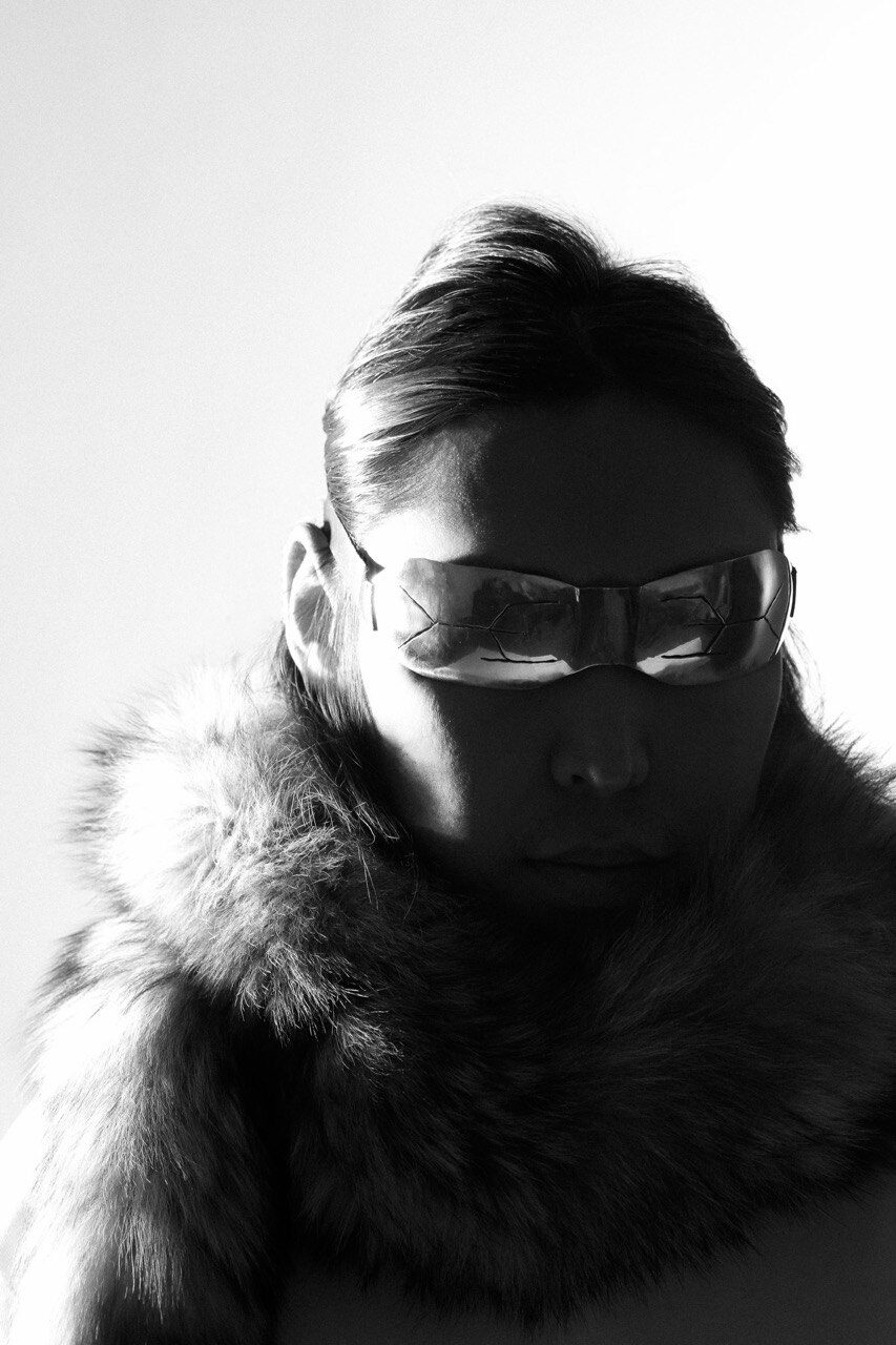 A portrait wearing sculpted silver snow goggles and a fur collar